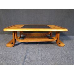 a wooden table with a glass top on grey carpeted floor next to gray wall