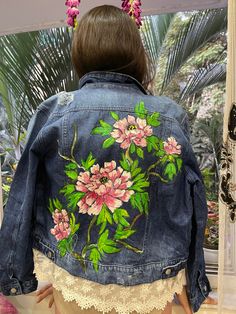 a woman wearing a jean jacket with pink flowers on it