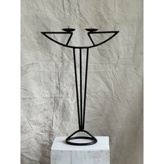 a black metal sculpture with three candles on it's sides and one candle in the middle