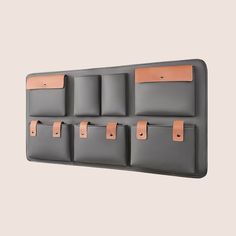 there is a wall mounted coat rack with five pockets and leather straps on it,