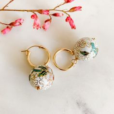 Add a unique touch to your look with our Floral Cloisonné Drop Hoop Earrings. These beautiful earrings feature rare cloisonné enamel beads, adding a playful pop of color to any outfit. Each pair is a wearable work of art, with subtle colors and removeable charms. A truly unique find! -- hoop diameter: 15mm and 19mm latch back cloisonné charms: 14mm and 18mm 14k Gold Filled available in white and black The ancient technique of cloisonné enamelwork is over 3,000 years old. Drop Hoop Earrings, Hoop Charms, Enamel Beads, Gold Filled Hoops, Pearl Gemstone, Pearl Wedding, Enamel Charms, Aruba, Silver Pearls