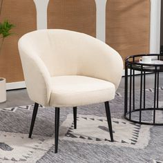 a white chair sitting on top of a rug next to a table and potted plant