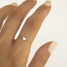 a woman's hand wearing a gold ring with a heart shaped diamond on it