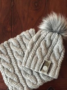 a knitted hat with a pom - pom on top sitting on a wooden floor