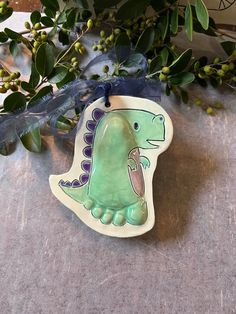 a ceramic dinosaur ornament sitting on top of a table next to green leaves