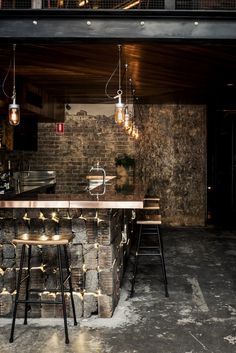 a bar with stools and lights hanging from it's ceiling in a dark room