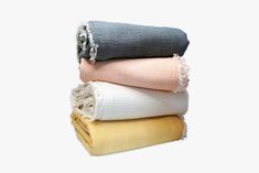 three folded blankets stacked on top of each other in different colors and sizes, with frayed edges