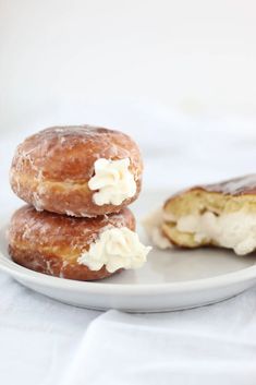 two donuts with icing and cream on a plate