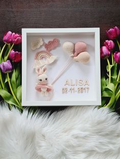 a white frame with pink flowers and two crocheted mice