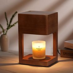 a candle that is sitting on top of a wooden stand next to some books and a potted plant