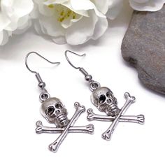 Dangly earrings with silver tone skull and bones charms. The earrings are ca 40mm (1.57 inches) long including hooks. Silver coloured hooks that comply with strict regulations for low nickel and lead content in jewellery. Bone Colored Metal Earrings For Pierced Ears, Silver Skull Earrings With Skull Print, Nickel-free Skull Earrings In Punk Style, Nickel Free Metal Skull Earrings, Metal Skull Earrings With Ear Wire, Skull-shaped Metal Earrings With Ear Wire, Silver Skull Earrings With Ear Wire, Skull Shaped Metal Earrings, Skull And Crossbones