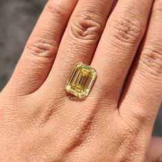 a close up of a person's hand with a yellow diamond ring on it