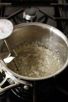 a pan filled with boiling water on top of a gas stove next to a thermometer