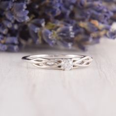 a close up of a ring on a table with flowers in the background and a purple flower