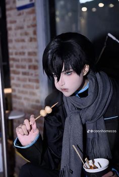 a young man with black hair is holding chopsticks in his hand