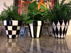 three black and white planters sitting on top of a counter