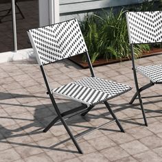 two black and white chairs sitting on top of a tiled floor next to a planter