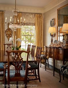 a formal dining room with chandelier, table and chairs in front of the window