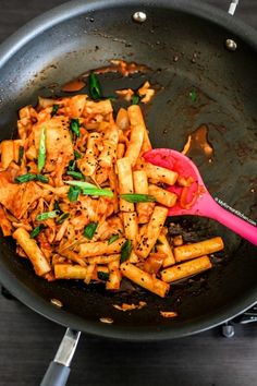 a skillet with some food in it and a pink spoon on the side that says minimalistic korean spicy rice cakes cookbook