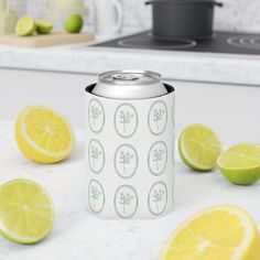 a can of soda with lemons and limes around it on a kitchen counter