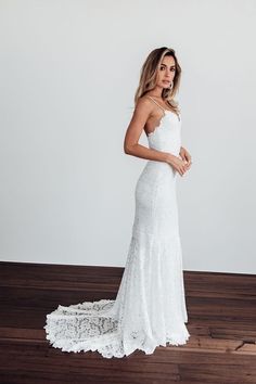 a woman in a white wedding dress standing on a wooden floor with her hand on her hip