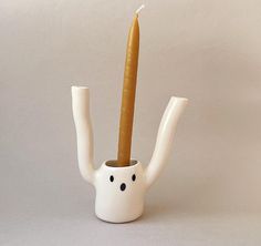 a white teapot with a carrot sticking out of it's side and a candle in the middle