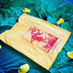 "Bella Canvas (3001CVC) Unisex Light Yellow Short Sleeve Tee. Single-color halftone screen print of the Fool Card from the Ryder-Waite Tarot Deck, but it says, \"WASSUP.\" Artwork Size: Approximately 5.5\"w x 9\"h From Bella Canvas' Website: This updated essential unisex heathered T shirt fits like a well-loved favorite, featuring a crew neck, short sleeves and designed with superior Airlume combed and ring-spun cotton that acts as the best blank canvas for printing. Features: Side-seamed. Retai Fool Card, Color Halftone, Yellow Short, Yellow Shorts, Tarot Deck, Shirt Fits, Blank Canvas, Tarot Decks, Light Yellow