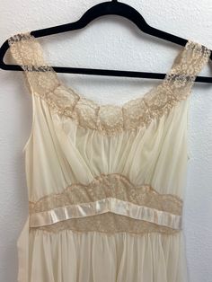 "1950's Vanity Fair Nightgown This cream colored nightgown is dreamy. She is a 1950's Vanity Fair size 32 Tricot Nylon two layer night gown trimmed in lace. She has two ribbon waist ties for decoration. Measurements provided are flat and have been doubled. Bust 32\" Waist 26\" Hips free Length 40\" ❤️ Condition: Excellent vintage condition. Flaw: waist tie ribbons have a few flaws, but they are not noticeable when worn. Please see pic. This item has been cleaned and is ready to wear. $68 include Vintage Nightgown With Delicate Lace For Wedding Night, Sleeveless Cream Nightgown For Wedding, Vintage Wedding Nightgown With Delicate Lace, Sheer Lace Cream Nightgown, Sleeveless Lace Nightgown In Cream, Vintage Cream Sleeveless Sleepwear, Vintage Cream Sheer Nightgown, Vintage Lace Nightgown For Sleep, Vintage Cream Nightgown For Sleep