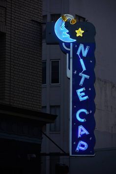 a neon sign that is on the side of a building in front of a building