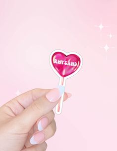 a hand holding a heart shaped lollipop with the word ruby sand on it