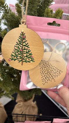 a wooden ornament hanging from a christmas tree in a pink package on top of a table