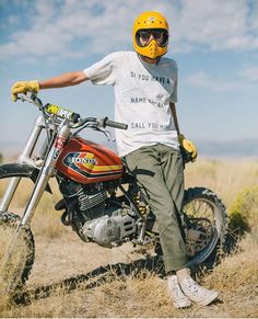 a man sitting on top of a dirt bike in the middle of an open field