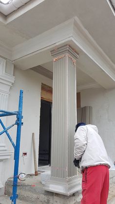 a man in white jacket and red pants working on a column