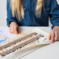 a woman is working on an art project with clothes pins and glues in front of her