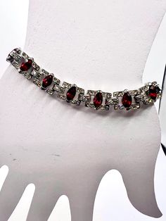 This stunning vintage bracelet is a must-have for any jewelry collection. The beautiful red navettes with clear chaton rhinestones are set in a silver tone bracelet that complements the overall design. The bracelet is perfect for women who appreciate vintage and antique jewelry, and it would make a great addition to any outfit. The bracelet's style is classic and timeless, with a chain that adds a touch of elegance to the piece. The country of origin is unknown, but the bracelet's quality and design speak for themselves. This bracelet is perfect for anyone who loves unique and beautiful jewelry Vintage Red Jewelry With Rhinestones, Vintage Red Rhinestone Jewelry, Formal Red Crystal Bracelets, Vintage Red Bracelets For Anniversary, Wedding Bracelets, Wedding Jewelry Bracelets, Vintage Bracelet, Bracelet Vintage, Vintage Bracelets