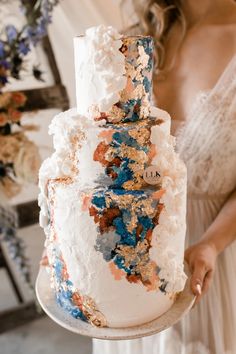 a woman holding a white and blue wedding cake