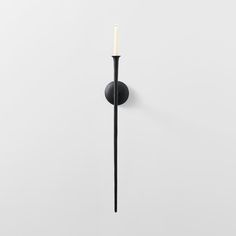 a single candle is lit on the wall in front of a white background with no one around it