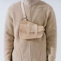 a person wearing a beige jacket with a small bag attached to the back of it