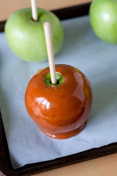 two apples with toothpicks sticking out of them on a tray next to another apple