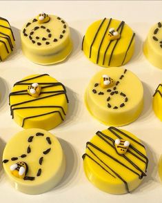 twelve decorated yellow and black cakes sitting on top of a white countertop next to each other