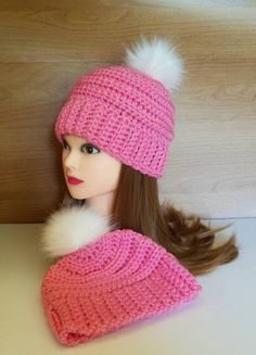 a doll wearing a pink knitted hat and scarf with white pom - pom