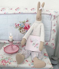 a stuffed rabbit sitting on top of a table next to a plate and candle holder