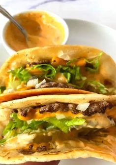 two tacos with meat, lettuce and cheese on them sitting on a plate