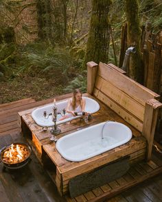 a woman sitting in an outdoor bathtub next to a fire pit