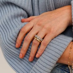 a woman's hand with two rings on her fingers, wearing a blue sweater