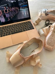 a laptop computer sitting on top of a bed next to ballet shoes and ballerinas