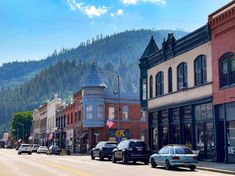 cars are parked on the street in front of buildings with mountains in the back ground