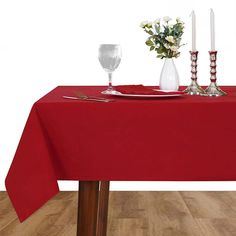 a red table cloth with silverware and flowers on it, along with two wine glasses