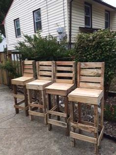 four wooden chairs sitting next to each other in front of a house