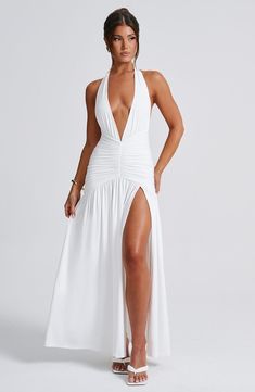 We're obsessed with Melania. our brand new maxi dress that beautifully hugs your figure over the bust and hips. with a gentle shaped skirt. It stands out for it's sleek. sexy details. including a plunge halter neckline. self tie to the back of the neck and low v-shaped back. The maxi is complete with a thigh high split and ruched detailing.   Colour: Ivory. Stretch double layered slinky fabric. Fully lined. Plunge halter neckline. Tie to back neck. Low V-shaped back. Fitted over hips with ruching. Hugs the figure. Loose. shaped skirt with thigh high split. Maxi length. Model is an XS and is wearing an XS. Chic V-neck Maxi Dress With Hollow Out, Elegant White V-neck Maxi Dress, White Fitted V-neck Maxi Dress, Luxury White V-neck Maxi Dress, White V-neck Sheer Maxi Dress, Homecoming Dresses Corset, Ivory Maxi Dress, Bodycon Evening Dress, White Maxi Dress